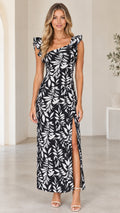 Front view of model wearing black and white leaf print ruffled strap maxi dress with side slit