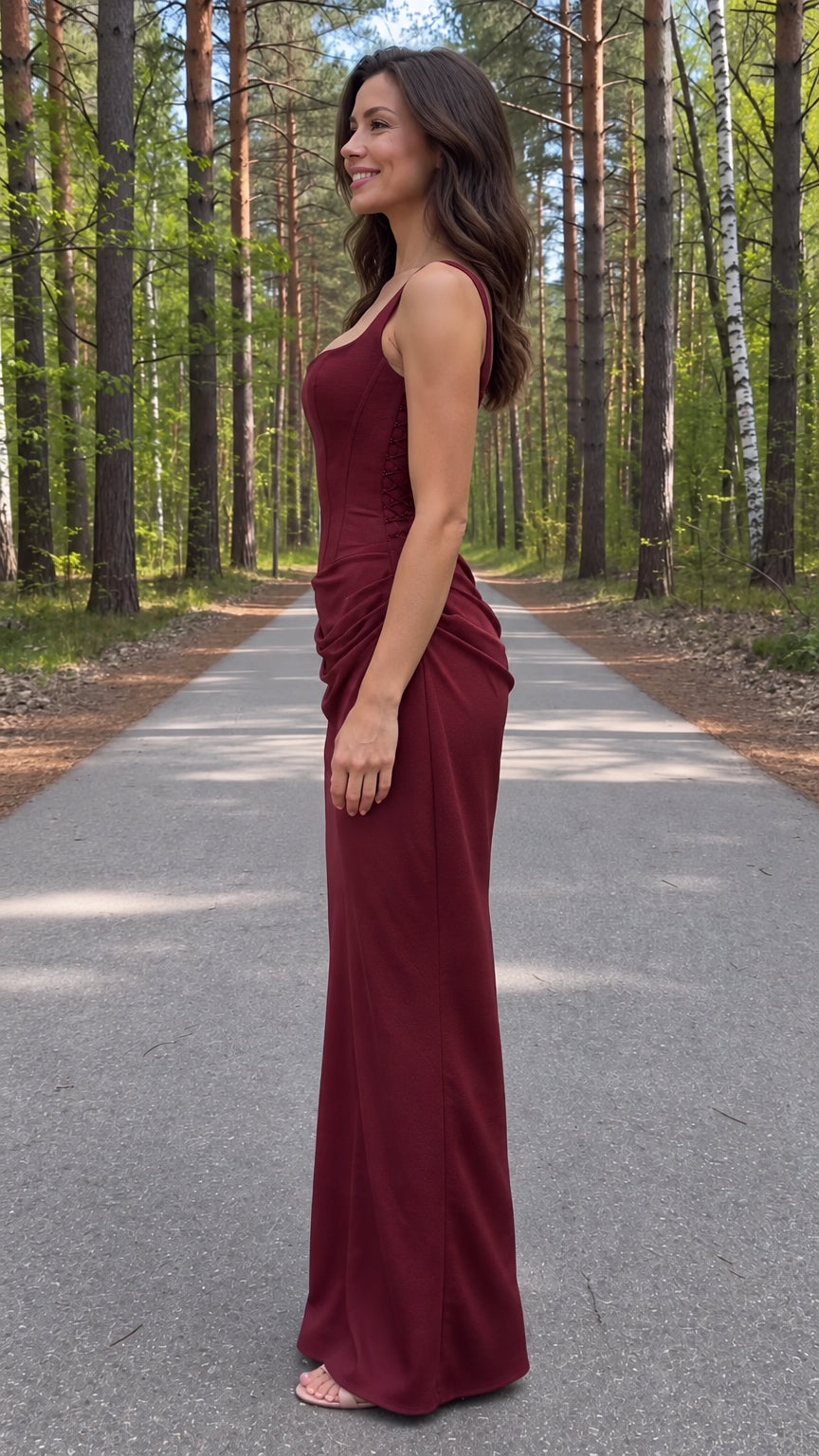Side view of model wearing a burgundy corset maxi dress showing sculpted silhouette